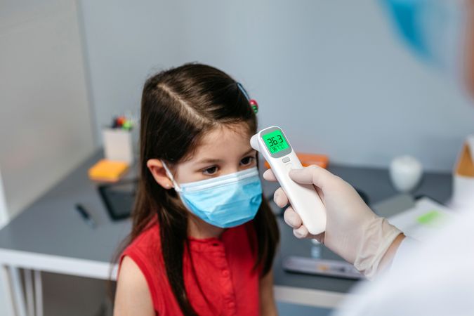 Girl without fever whose temperature is taken by her doctor