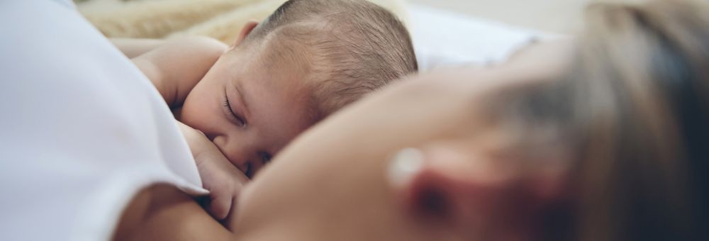 Newborn lying on the bed with her mother