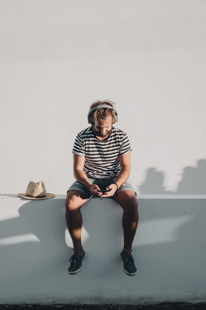 Young male sitting with smartphone and headphones