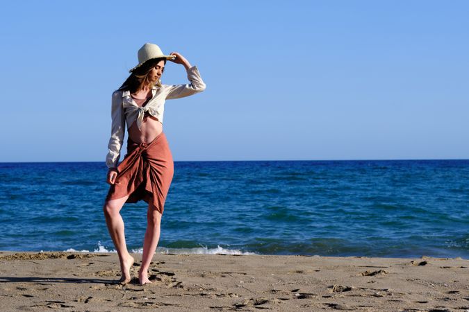 A fashion model with a hat at the beach before sunset