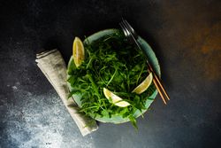 Top view of fresh arugula salad with fresh lemon slices