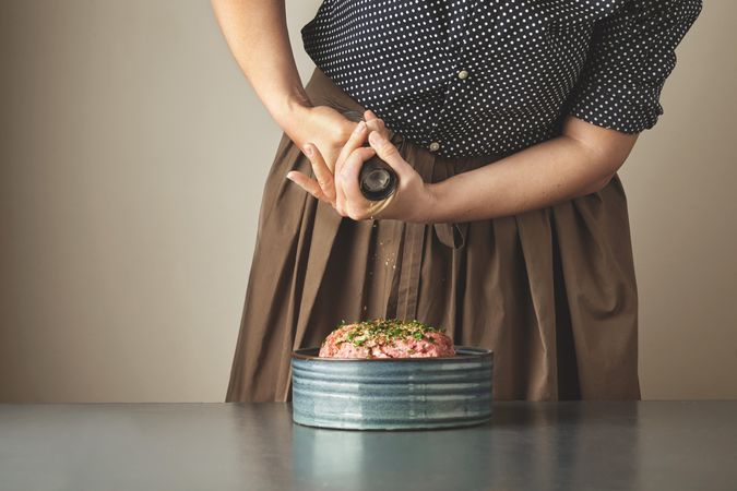 Woman grounding pepper into ground beef