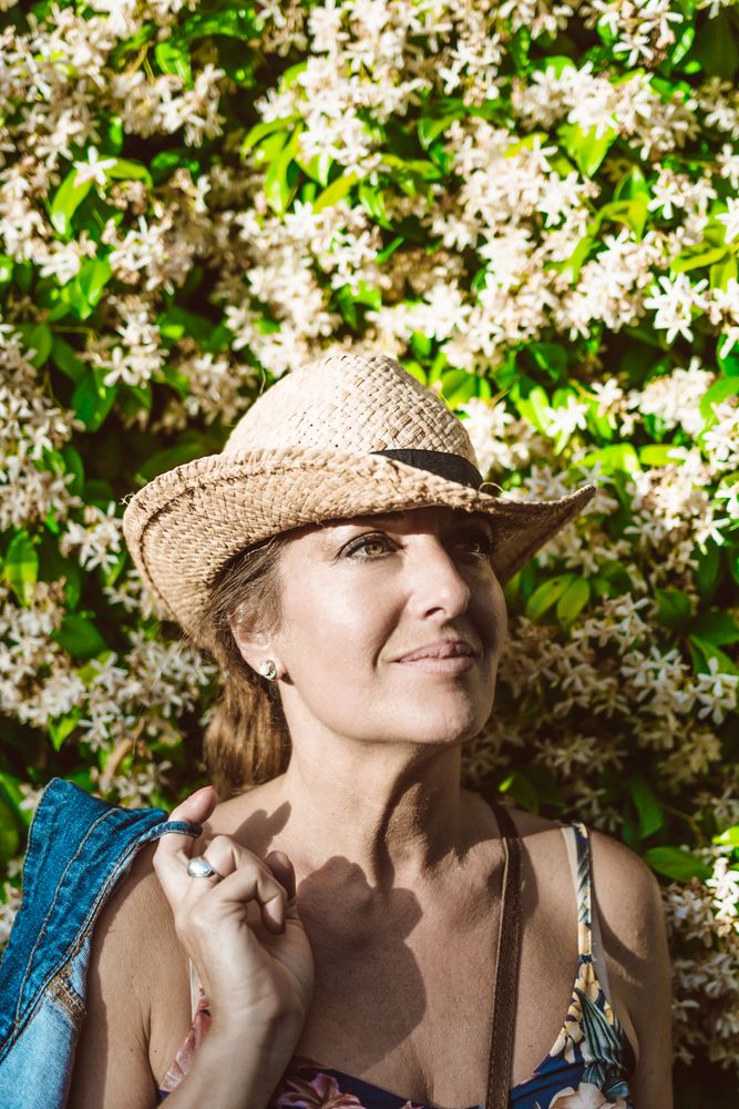 Woman standing near a wall with flower shrubs