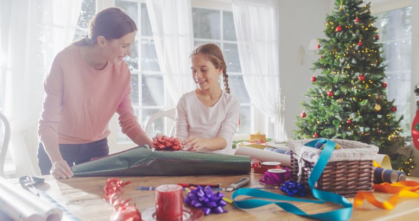 Portrait of Mother and Daughter Wrapping Gifts for Christmas at Home.