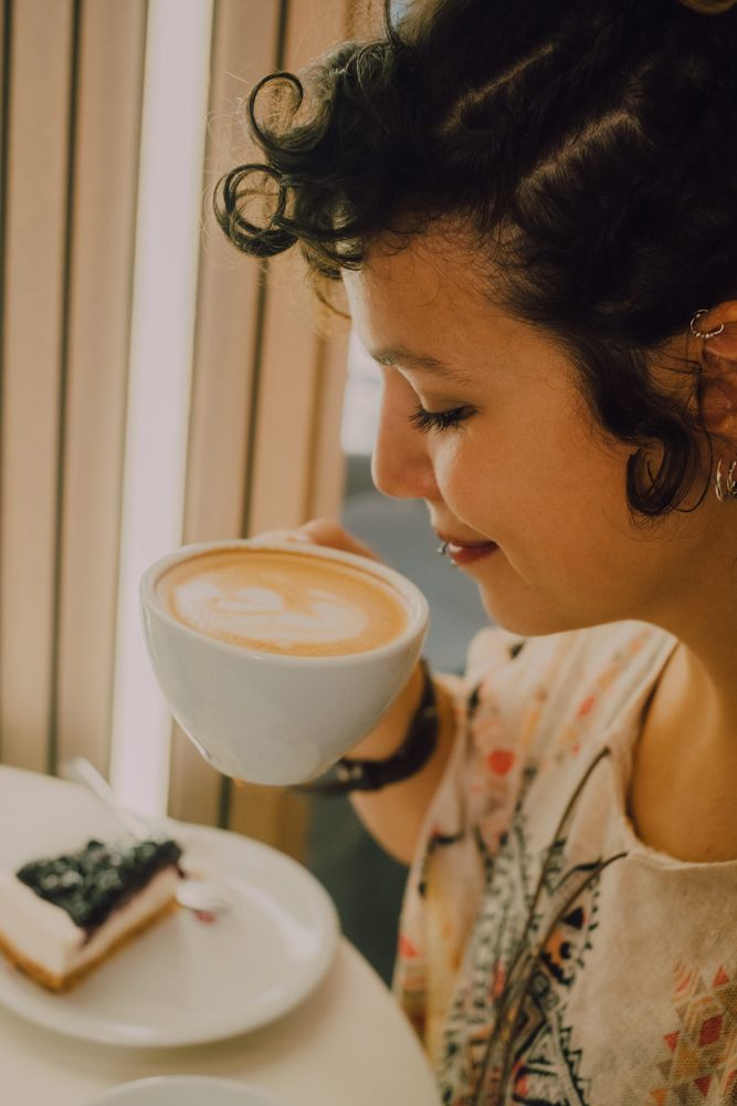 Positive woman drinking coffee in cafe