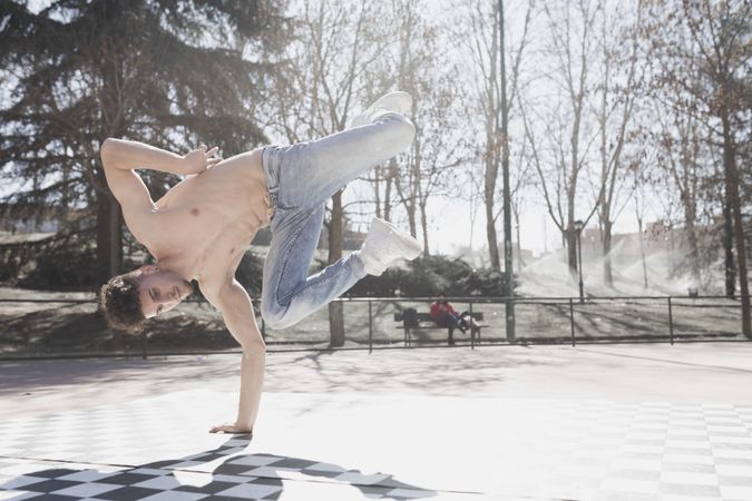 Shirtless man dancing break dance in park