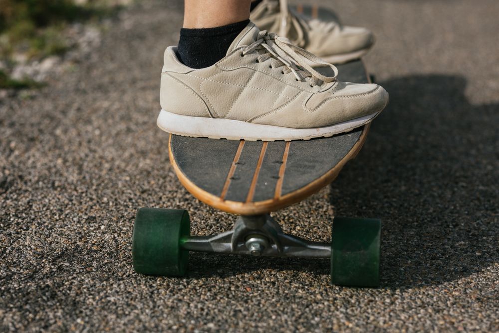 Anonymous woman riding longboard on asphalt road