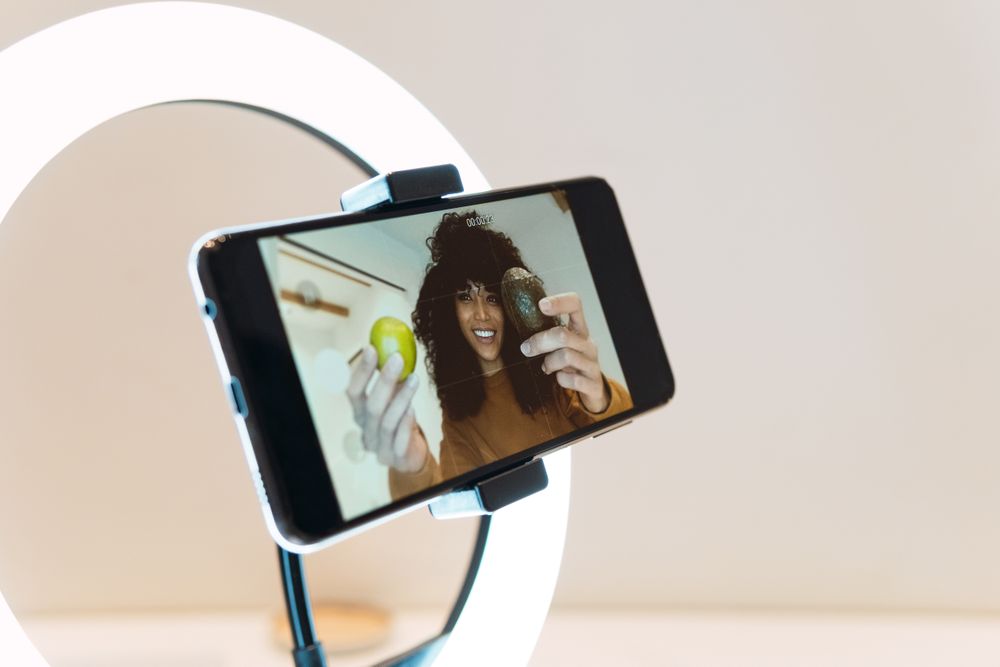 Cheerful Black women filming blog on smartphone
