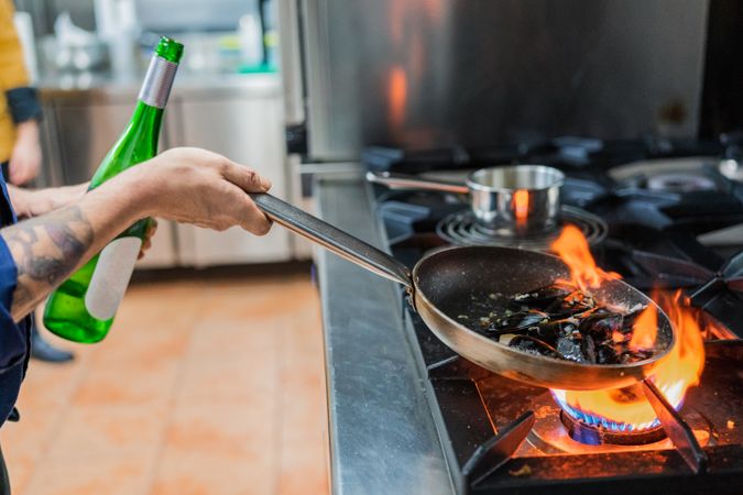 Chef cooking with flame in frying pan