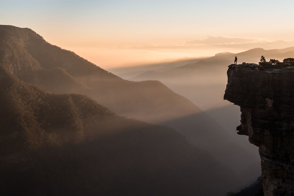 Man standing on cliff near mountains