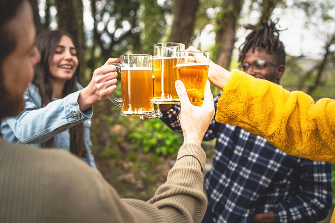 Smiling multi-ethnic group of friends gather outside to chat and have a beer together