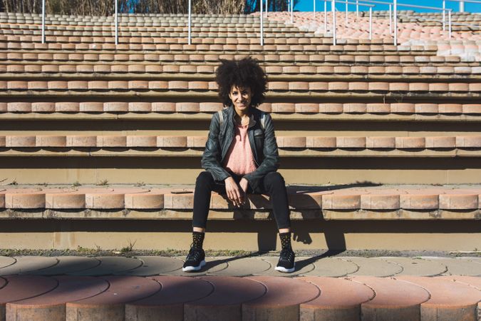 Woman with afro hair sitting on the steps of a stadium