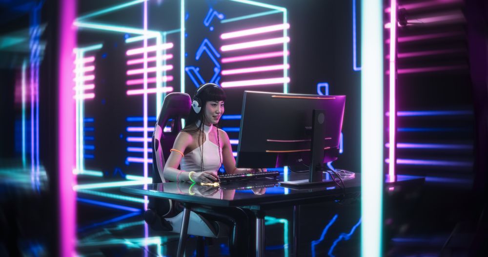 Portrait of a Japanese Young Female Wearing Headphones, Talking with Friends Online on a Computer.