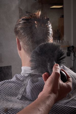 Faceless barber removing hair from client