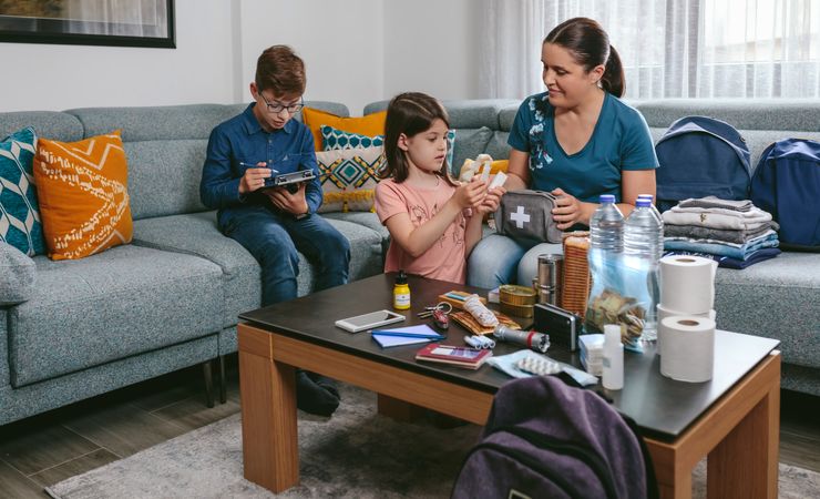 Mother preparing emergency backpack with her children