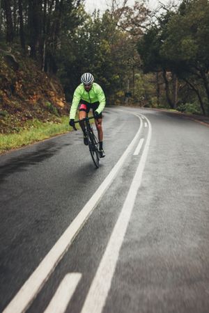 Bicycle rider with bike on wet asphalt road