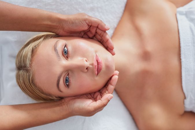Blonde woman looking up while receiving facial treatment