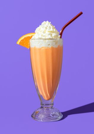 Orange milkshake glass minimalist on a purple background