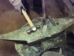 Crop forger working on anvil with hammer and sickle