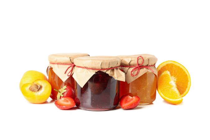 Glass jars with jam and ingredients isolated on blank background