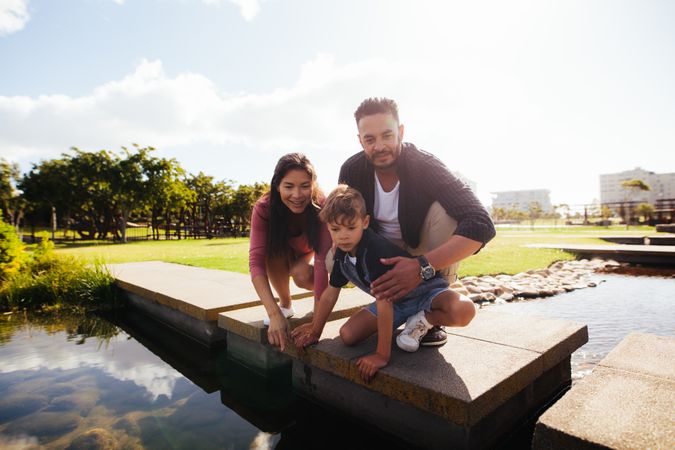 Portrait of family in cheerful mood happily playing by a river in a park
