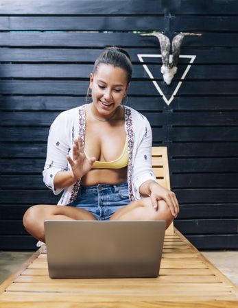 Relaxed woman using laptop while resting on deck chair