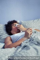 Sick man blowing nose and checking temperature in bed 56Gvyx