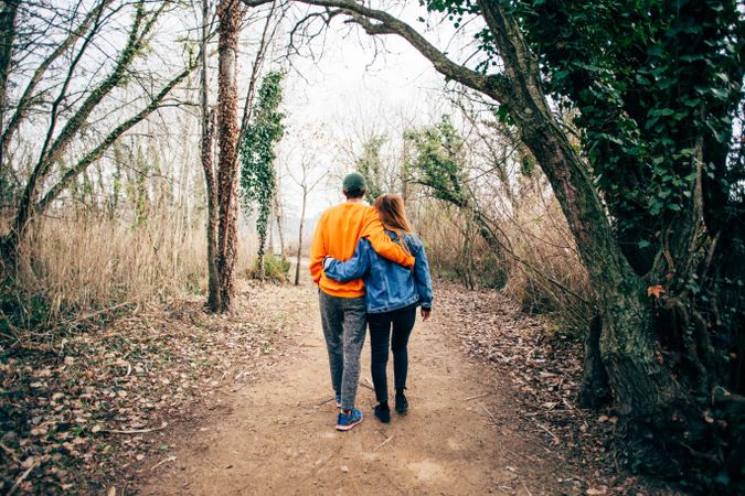 Back of loving couple walking on a forest trail