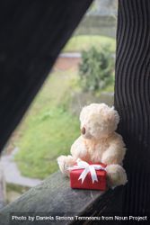Stuffed toy with a gift on a wooden beam bYMogb
