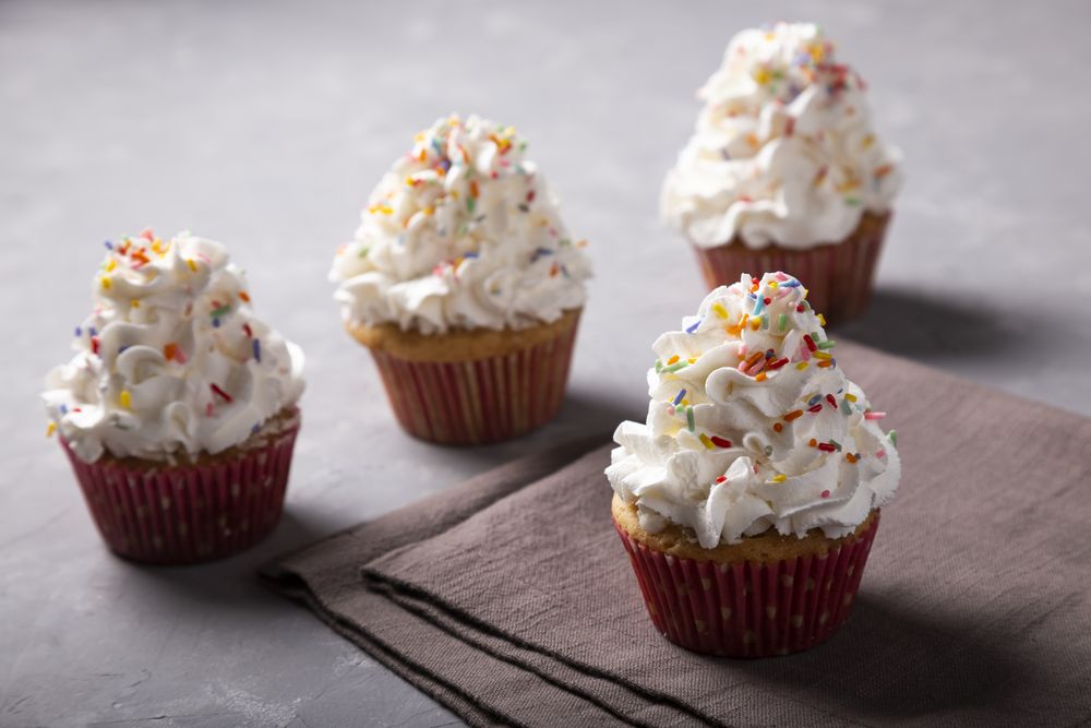 Tasty party cupcakes on the table. Cupcakes with whipped cream.