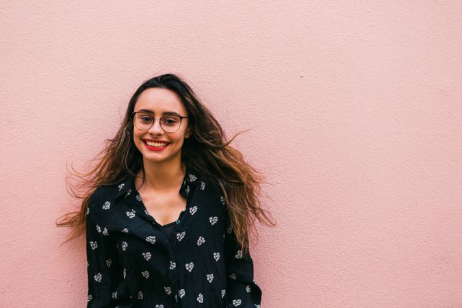 Smiling young woman against pink wall