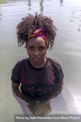 Beautiful Black woman with headscarf in water and looking at camera bxAved