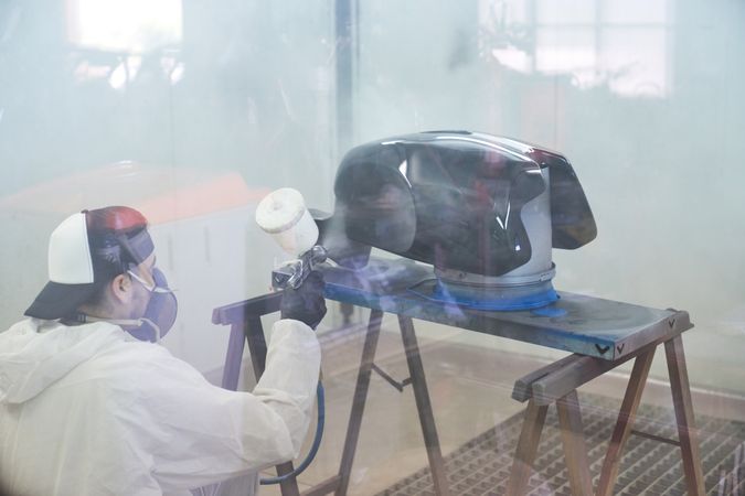 Unrecognizable male mechanic painting motorbike tank