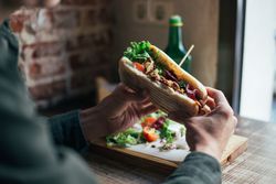Hands holding delicious sandwich in cafe