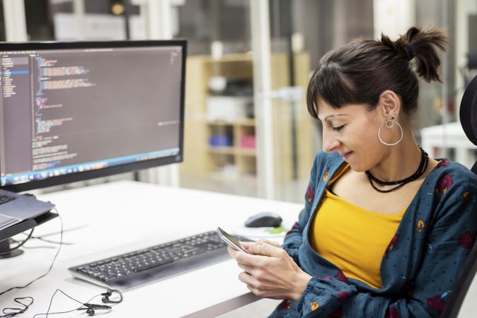 Businesswoman using smartphone near laptop