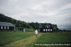 Back of man walking on grass towards house on overcast day 4dXdr4