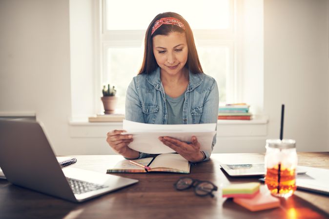 Content woman reading notes in home office