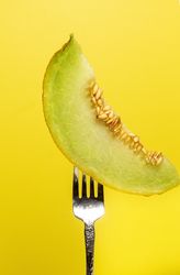 Piece of melon strung on shiny fork