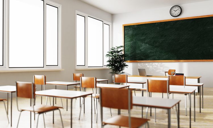 Empty chairs in classroom looking towards the teacher’s desk