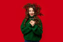 Girl in green sweater holding two candy canes shaped heart