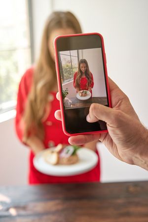 Unrecognizable person taking picture of young woman