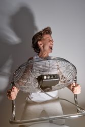 Excited boy screaming in front of blowing fan