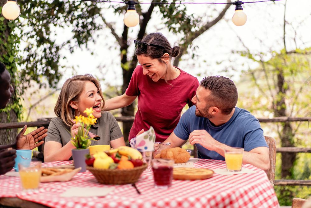 Group of diverse friends laughing and enjoying a picnic, sharing a moment of joy and casual dining