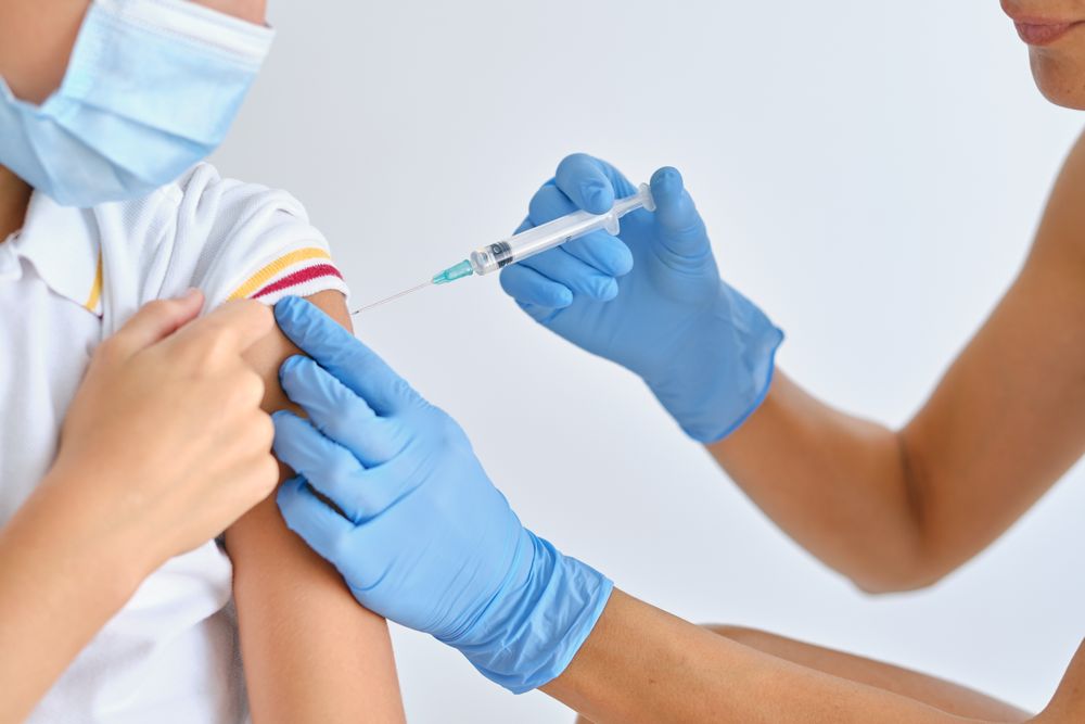Unrecognizable nurse injecting coronavirus vaccine into shoulder of patient