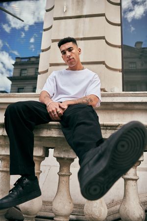Stylish young man in light t-shirt sitting on stoop in London