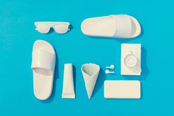 Summer objects of flip flops, sunglasses, camera, smart phone, EarPods on blue background
