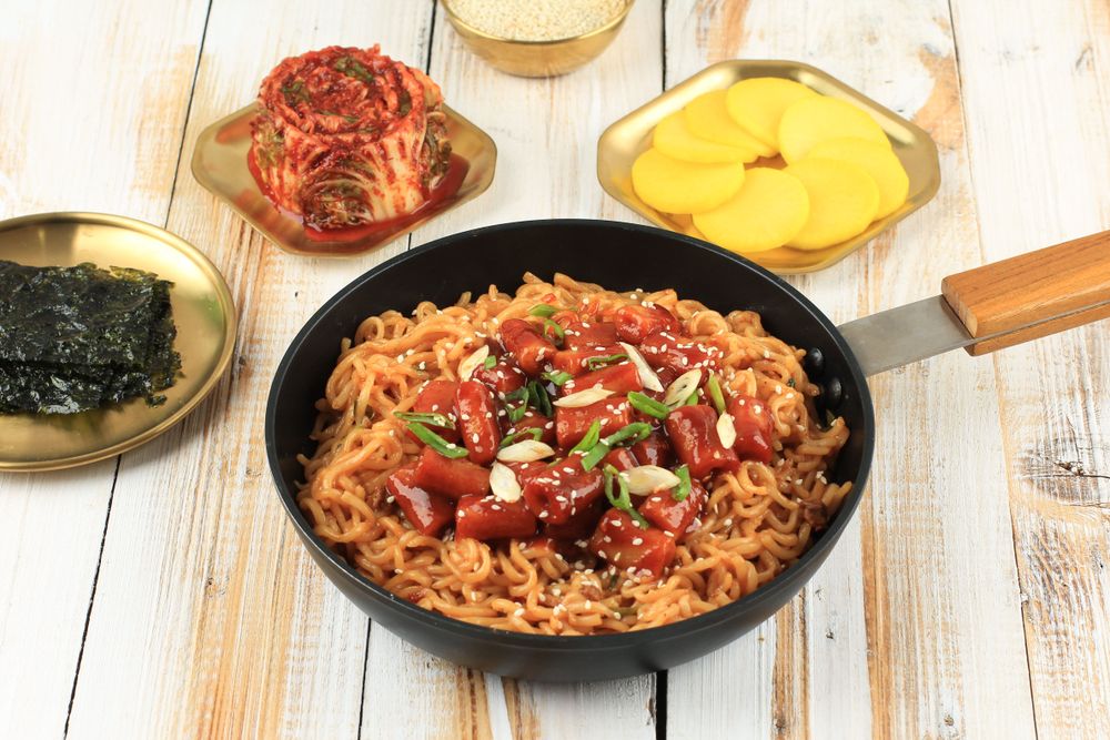 Pan of noodles topped with Korean rice cakes served with condiments