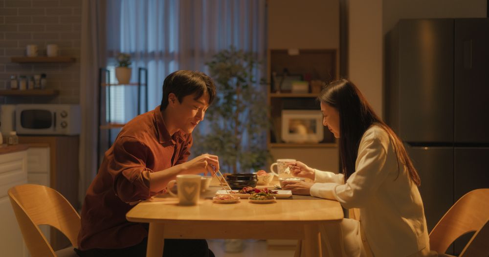 Young Loving South Korean Couple Eating Homemade Tasty Food at Home and Having a Fun Chat.