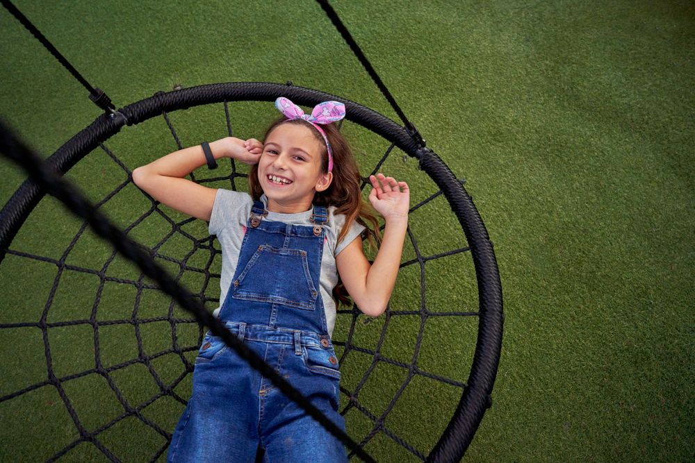 Smiling girl lying on web swing