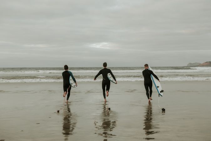 People with surfboard walking near sea